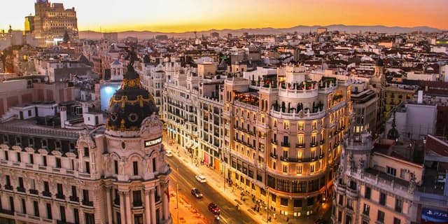 Madrid’s Metrópolis dome and Gran Vía glowing beneath a rose-and-gold sunset.